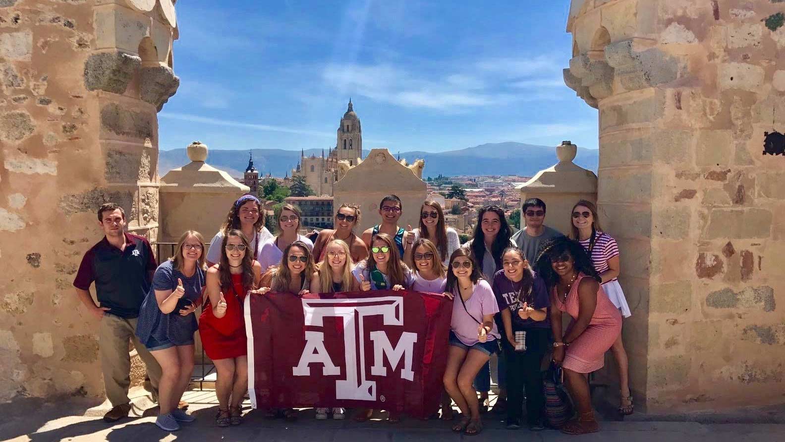 Study abroad students hold a ϲʹ̳ flag up while taking a picture
