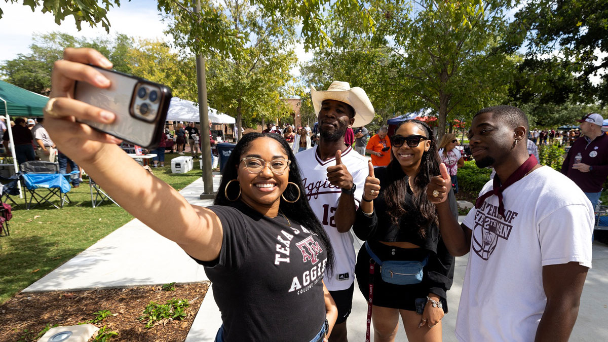 Four ϲʹ̳ studdents pose for a selfie while tailgating at an Aggie football game