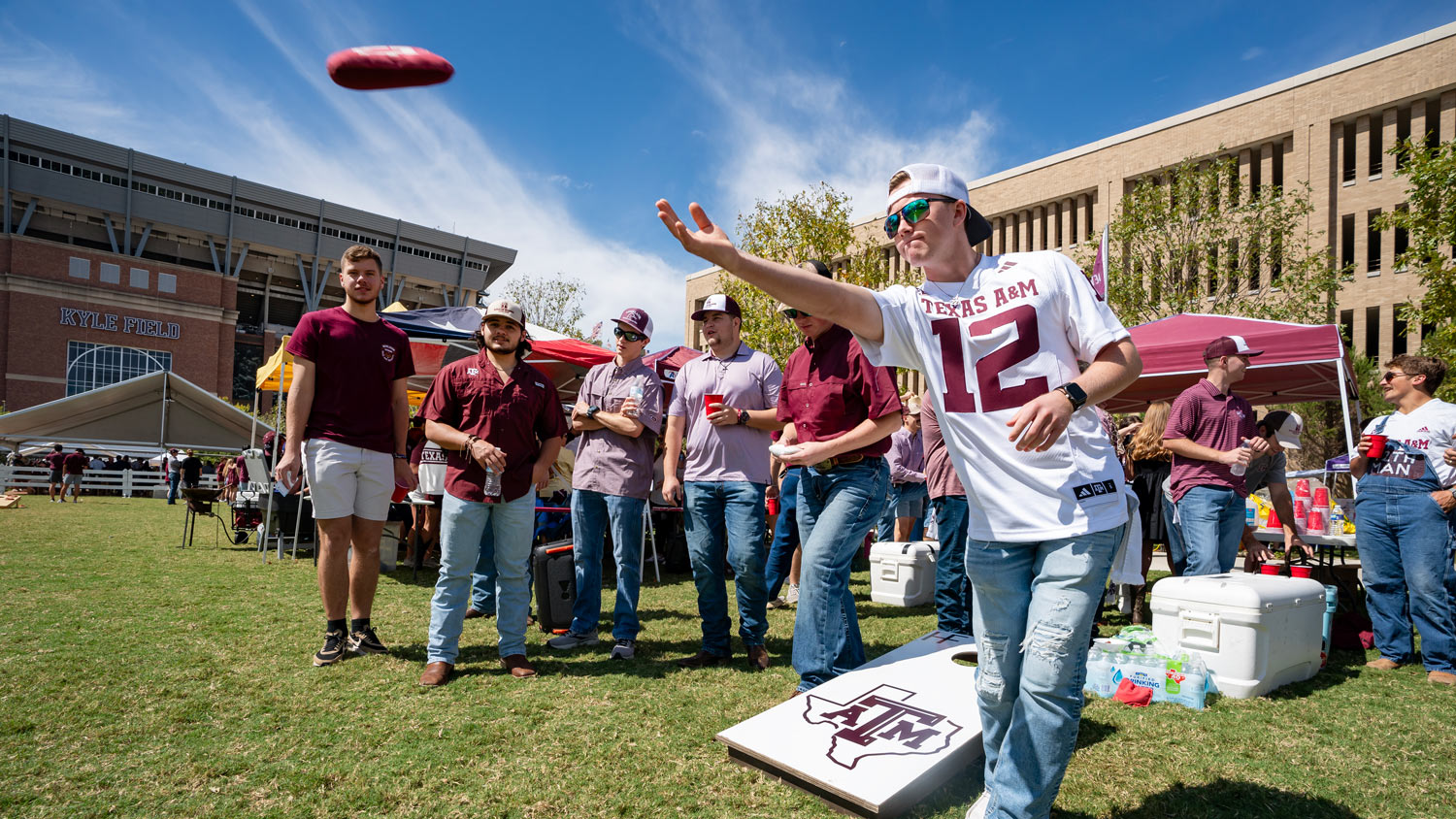 A group of students play cornhole at a ϲʹ̳ tailgate