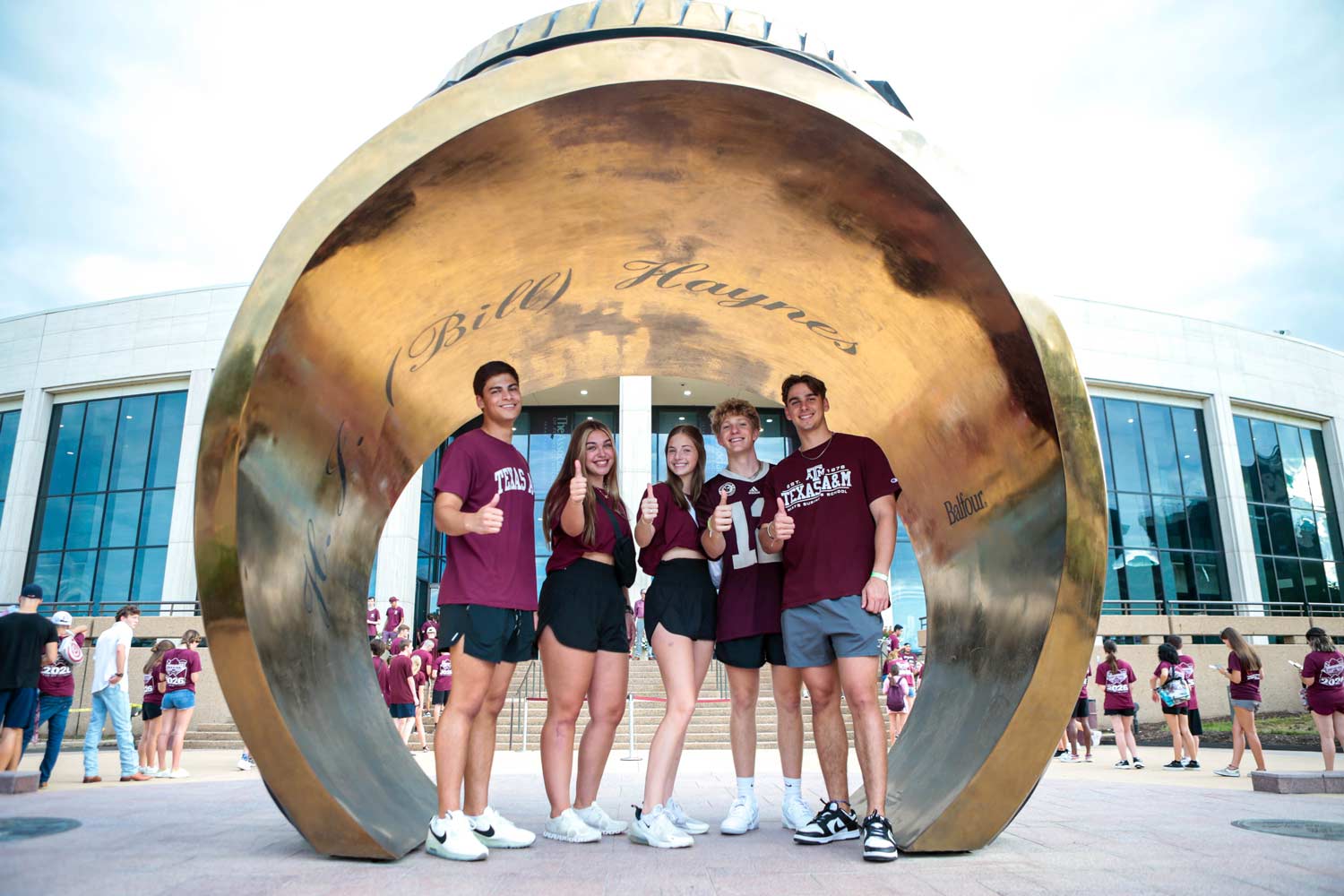 ϲʹ̳ University students posing under the Association of Former Students Ring Statue