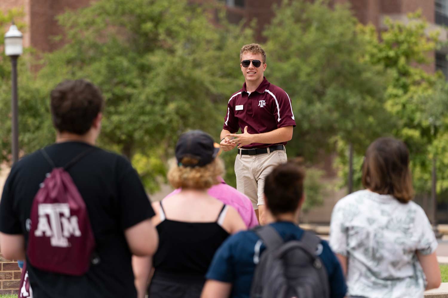 ϲʹ̳ tour guide stands on a bench to address the crowd of prospective students